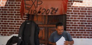 Fernando Gaitán ajusta su silla de plástico bajo una lona raída. Lleva seis años esperando justicia frente a la planta donde trabajó 26.